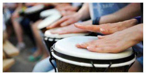 Close-up of multiple people playing hand drums.