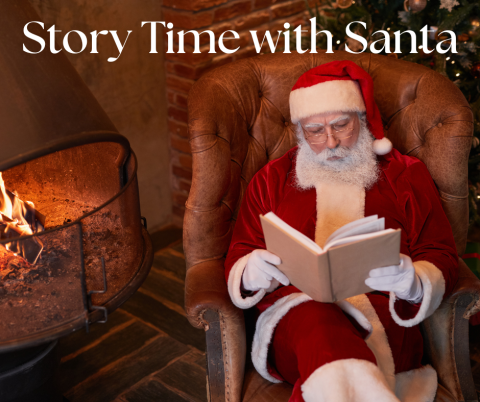 Photo of Santa sitting in a chair and reading a book next to a fireplace.